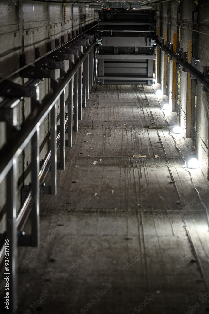 Fototapeta premium Industrial elevator shaft with illuminated pathway and metal framework