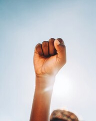 Raised Clenched Fist of a Person of Color Against a Clear Blue Sky Symbolizing Freedom and Strength, Ideal for Juneteenth and Social Justice Campaigns with Copy Space