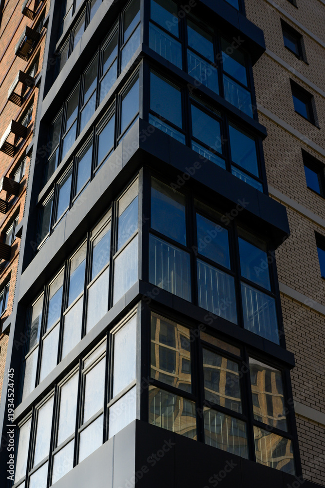 Obraz premium Modern building corner with large glass windows and brick facade