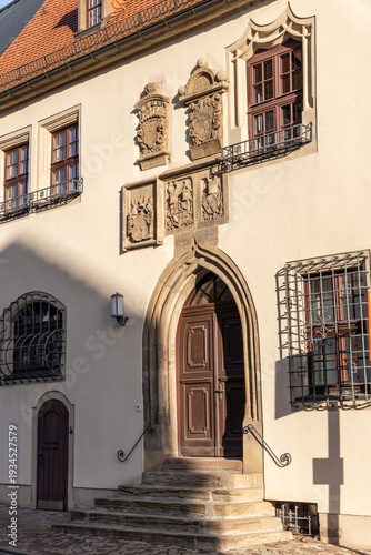 Side view of the entrance to the Old Town Hall in Merseburg, Germany. Stairway leading to a heavy door with ornate decorations above the portal.
