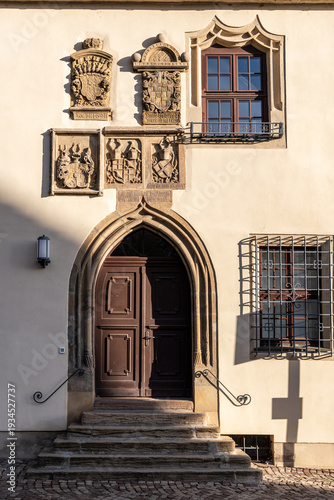 Entrance to the Old Town Hall in Merseburg, Germany. Stairway leading to a wooden door with a coat of arms above the portal and windows with grilles.