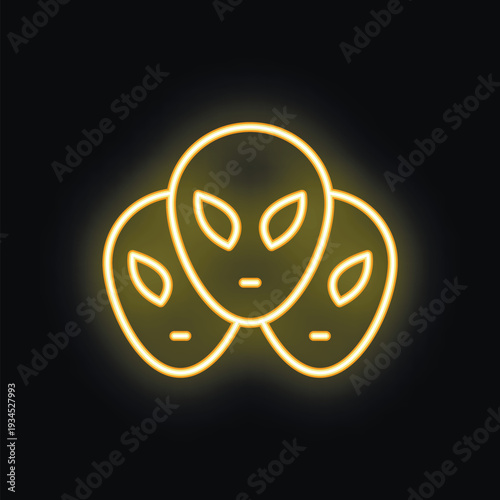 Yellow neon sign representing three alien faces glowing on black background