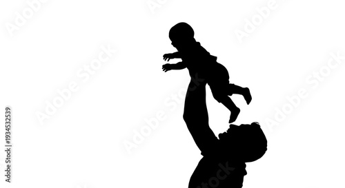 Silhouette of man holding baby up.