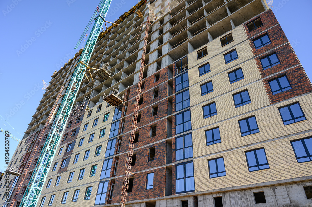Fototapeta premium High-rise building construction with crane and scaffolding