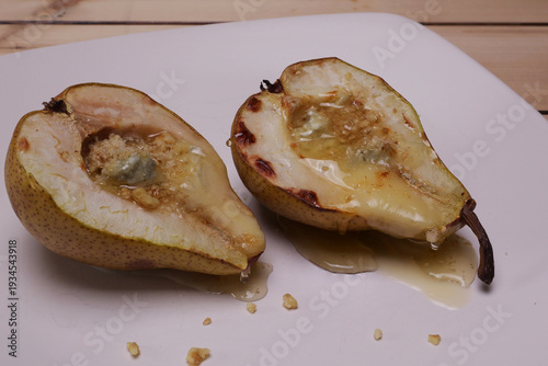 Piatto con pere cotte al forno ripiene di formaggio, granella di noci e miele
