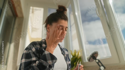 Casual woman gently applying drops before virtual meeting