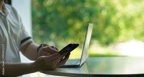 Person Using Smartphone Next to Laptop