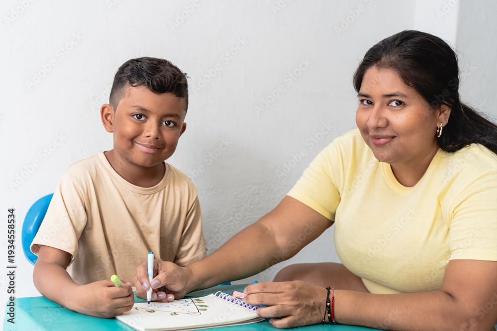 Fototapeta premium Mother and son coloring in notebook learning together