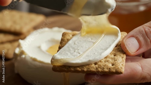 Honey drizzling over cream cheese with crackers on wooden surface