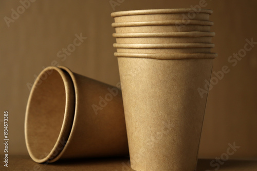 Canvas-taulu Stacked paper cups on a brown background with one cup tipped over