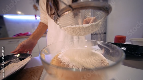 Focused hands sift fine flour onto egg batter during calming baking process