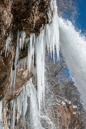 Large icicles and other ice formations adorn waterfalls at Rifle Falls State Park in Western Colorado on clear cold winter morning..