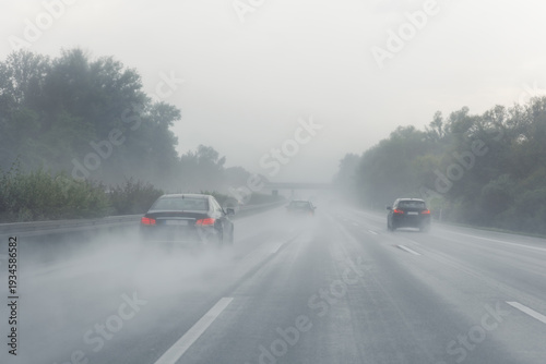 Back tail view of many cars driving fast on wet highway road after rain in Europe. Automobile accident vehicle rush hour collapse. Transportation vacation seasonal stuck. Low visibility bad weather
