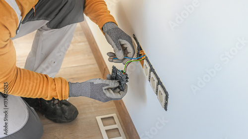 Electrical installation. An electrician's hands during installation a wall sockets to multi pack socket. 