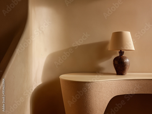 A lamp on a minimalist table casting a shadow on a beige wall from a low viewpoint indoors