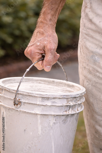 Close up of painter carrying paint bucket