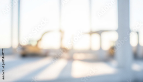 This image shows a blurred view of a construction site with large machinery and natural light streaming through windows, creating a bright atmosphere.