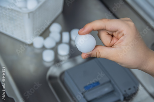 Fotografi Woman's hand putting water softener salt tablets into dishwasher to prevent lime