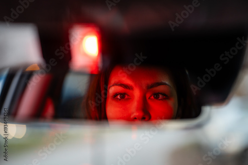 Foto Woman driving car at night seeing red light in rearview mirror