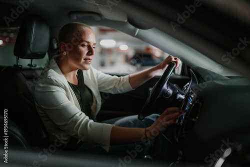 Quadro em tela Confident bald woman driving car and operating modern infotainment system in par