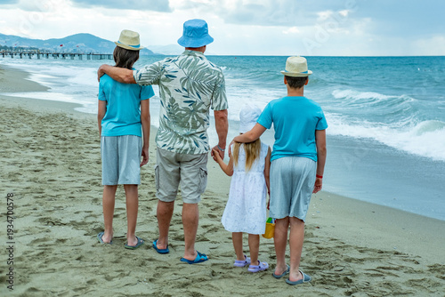 Schilderij op canvas Happy large family standing on sandy beach, looking out ocean waves together, fa