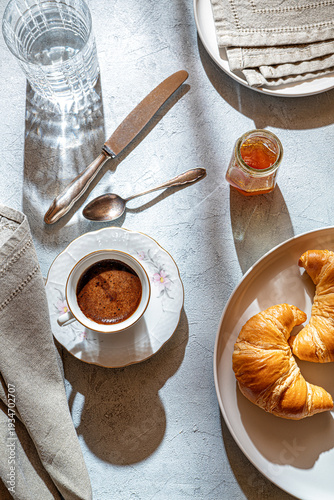 A cup of coffee, fresh croissant, honey on a table with sunlight. Table set for breackfast. Flat lay.