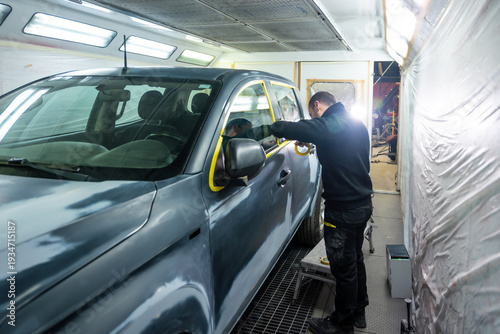 Schilderij op canvas Mechanic applying masking tape on car in paint shop