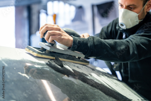Photos Auto body repairman sanding car surface with protective mask