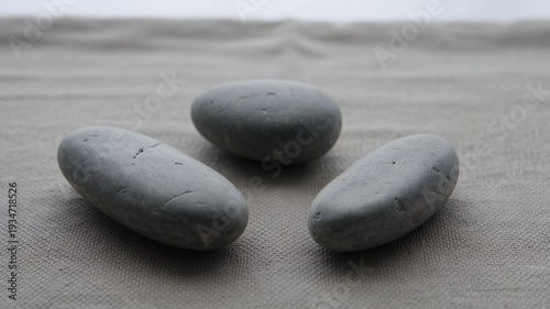Three smooth, grey stones arranged on a textured, neutral surface