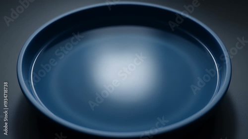 A minimalist, abstract, close-up view of a deep blue plate with smooth, reflective curves and soft lighting