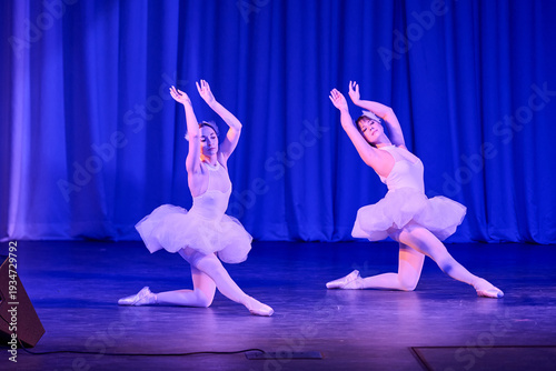 Foto Two ballerinas performing swan lake ballet in white tutus on blue stage