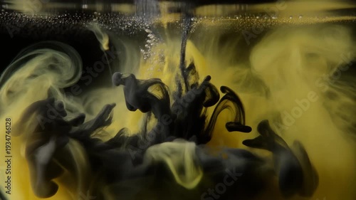 Ink splashing into water creating abstract patterns in yellow and black hues from a high-speed camera viewpoint.