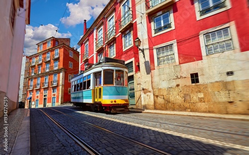 Lisbon, Portugal. Vintage red retro tram on narrow bystreet tramline in Alfama district of old town. Popular touristic attraction of Lisboa city. Public tramways trasport.