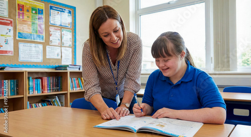 Professional female teacher explaining lesson to young woman with Down syndrome. Inclusive education and special needs learning concept in school.