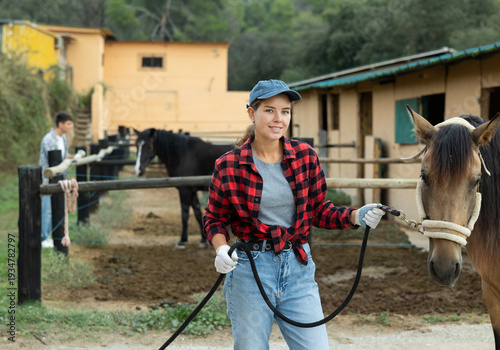 Photos Portrait of female owner of horse farm shows her farm against the backdrop of co
