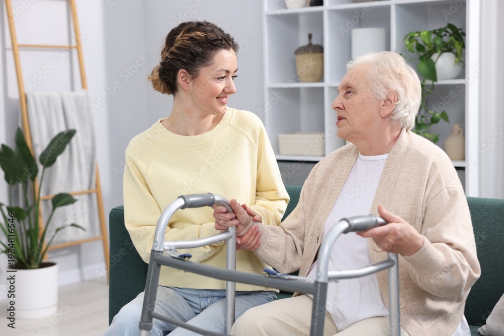 Fototapeta premium Caregiver helping senior woman with walker indoors