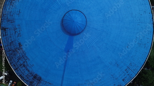 High angle drone photograph of a large water storage facility in a populated neighborhood with palm trees and homes.
