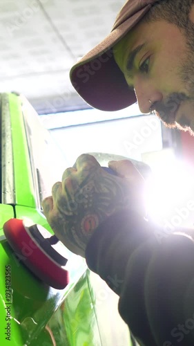 Tattooed auto detailer polishing a green car bodywork