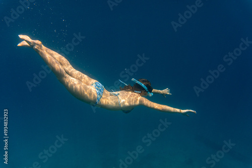 Fotografija A young woman snorkeling in clear deep blue tropical water during a diving excursion on Príncipe Island, São Tomé and Príncipe