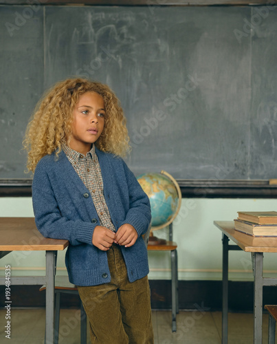 Thoughtful young student with curly hair in a vintage classroom