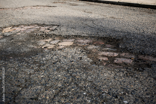 Quadro su tela Severe Road Damage Revealing Historic Cobblestone Pavement