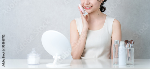 Fényképezés Smiling Asian woman applying foundation, powder and makeup