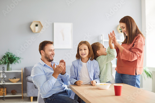 Parents and kids enjoy leisure time at home, playing a game together. The family celebrates victory with joy, sharing moments of fun and bonding while spending time together during the activity.