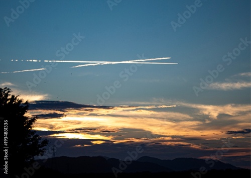 Bild auf Leinwand Sunset with airplane condensation trails