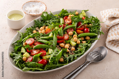 Fresh vegetables and quinoa salad with chickpeas, arugula and fresh peas with avocado ranch dressing