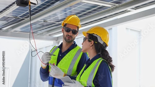 Maintenance engineers team in safety uniform discussing solar farm installation and efficiency, Engineers inspecting solar panel maintenance and electrical system check on rooftop