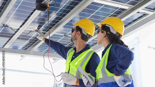 Engineers using multimeter and tablet to test photovoltaic system wiring, Technicians performing diagnostic tests solar panel infrastructure, Team of experts collaborating on solar energy maintenance