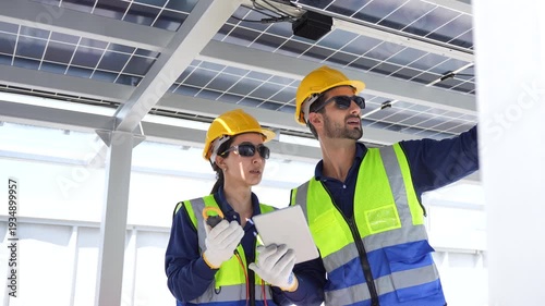 Maintenance engineers team in safety uniform discussing solar farm installation and efficiency, Professional technicians team working with digital tablet at solar power station for renewable energy