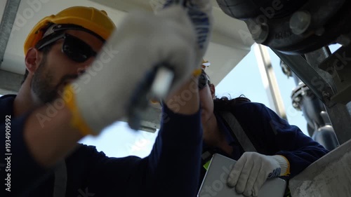 Professional technicians performing routine maintenance and repairing on industrial valve and pipeline system, Engineering team using tablet and wrench to coordinate repairs on water cooling system