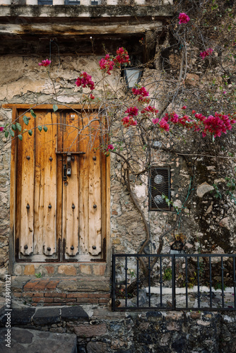 Rustic stone house with wooden door and bougainvillea in a traditional Mexican village